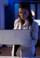 Executive boss typing on laptop late at night in business office working on financial reports. Focused manager using modern technology network wireless doing overtime for job searching photo