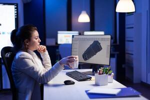 Project designer engineer analizing concept idea of 3D model of the plant yawning working overtime. Industrial woman worker studying turbine idea on pc showing cad software on device display photo