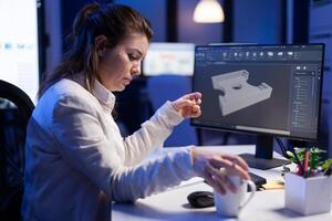 Software engineer working at digital cad project late at night in office company. Woman entrepreneur looking at technical construction before deadline using modern technology network photo