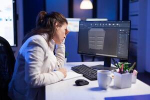 Engineer looking at cad software 3D prototype design concept of container working overtime in construction company. Overworked woman studying in office new project model using innovative technology photo