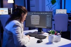 Focused architect working in 3D software developing prototype container design sitting at desk in business office. Technician engineer creating and studying project prototype, analysing scale model photo