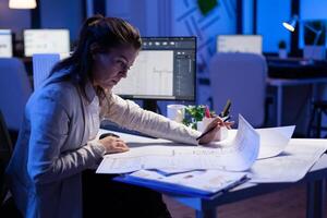 Over the shoulder shot of engineer woman drawing architectural plans and looking at cad software on desktop computer. Designer using arhitecture blueprints of buildings creating industrial prototype photo