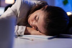 Entrepreneur working overtime on marketing project, falling asleep on desk while looking at financial documents trying to respect the deadline. Employee using modern technology network wireless photo