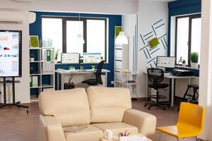 Interior of empty creative office with dusky light, new business, start up company with no people in it. Modern design and confortable couch with nobody in it, place of work startup photo