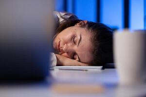 Entrepreneur working overtime on marketing project, falling asleep on desk while looking at financial documents trying to respect the deadline. Employee using modern technology network wireless photo