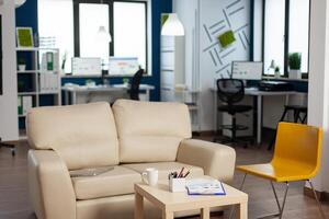 Interior of empty creative office with dusky light, new business, start up company with no people in it. Modern design and confortable couch with nobody in it, place of work startup photo