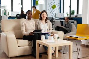 Start up company teamwork talking during meeting sitting on couch listening and explaning to remote manager team strategy. Multiethnic coworkers discussing about startup financial project. photo