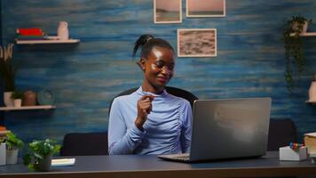 Smiling african american freelancer listening music working on laptop dancing sitting at desk in living room workplace. Black woman enjoy e-learning process, easy application usage overtime. photo