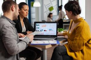 Business people talking with team leader using clipboard with documents pointing on it, presenting startup financial ideas to manager, brainstorming project management strategy in company office photo