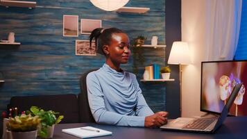 African lady explaining rules during webinar sitting in front of computer working from home overtime. Black employee discussing with business remotely team having virtual online conference. photo