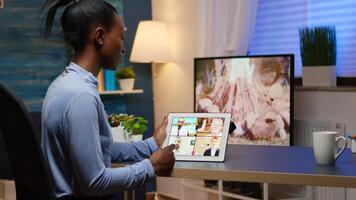 African business woman having webinar studying from home using internet technology on tablet in midnight. Lady using notebook with network wireless talking on virtual meeting at night doing overtime photo