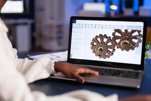 Close up of mechanical gears while engineer working with software for mechanism design. Freelancer studying prototype idea on pc showing cad software on device display. photo