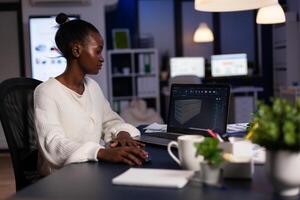 Black woman engineer designer looking at laptop analysing project using new software to design 3D concept of container working overtime in start-up company for prototype. Overworked worker studying. photo