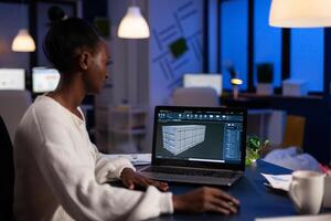 Black freelancer architect working in 3D software to elaborate container design sitting at desk in business office at midnight. Focused engineer creating and studying prototype, analysing scale model. photo