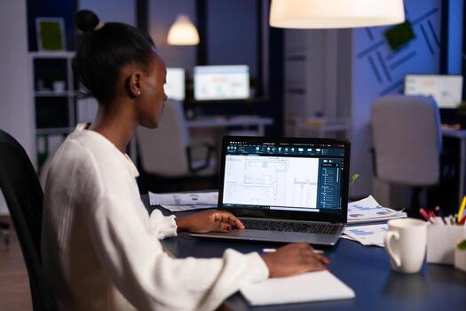 Black architect using cad softwer to build buildig plan, blue prints. Industrial woman employee studying prototype idea showing cad software on device display. photo