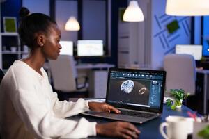 Black woman in mechanical industry working late at night doing overtime in start-up office. Industrial engineer studying prototype idea on pc showing cad software on device display. photo