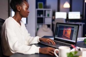 African gamer creator testing game over level interface, developing new design in midnight from business office using laptop. Player testing online games with technology network wireless. photo