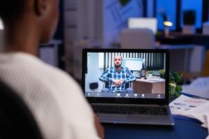 African american entrepreneur talking with remote partner discussing management strategy during videocall meeting conference. Online call teleconference telework on laptop computer photo