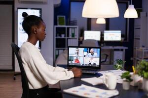 African american businesswoman having online business meeting with remote partners discussing company strategy during videocall conference. Teleconference call on laptop screen in office photo
