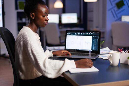 Focused african american arhitect engineer developing cad building architecture analyzing blueprint design plan working in startup engineering office late at night. Industrial prototype idea photo