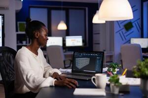 African american design arhitect working in 3D software developing prototype container idea working at night in corporate office. Technician engineer creating digital industrial project photo