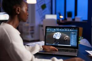 African american engineer developing engineering gear design working at industrial mechanical prototype late at night in startup company office. Project designer using industry construction software photo