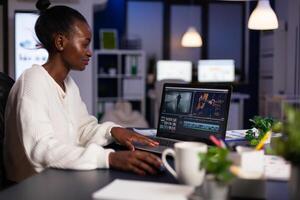 African american editor working late at night at digital movie project editing audio film montage in in creativity start-up business office. Videographer using post production software photo