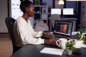 African american game developer testing new game working late at night in creativity agency company. Tired creator designer developing online games on pc using modern production technology photo