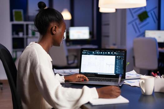 Focused african american arhitect engineer developing cad building architecture analyzing blueprint design plan working in startup engineering office late at night. Industrial prototype idea photo