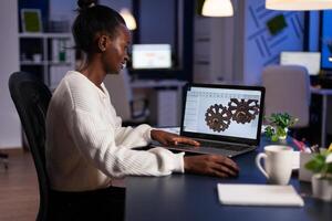 African american architect working industrial new project working at gear prototype late at night in start-up engineering office. Engineer woman developing technical construction product photo