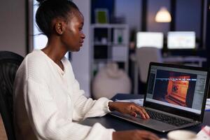 African american videogame designer working at virtual game graphics using gaming software production late at night in creativity company agency office. Virtual game montage on monitor photo