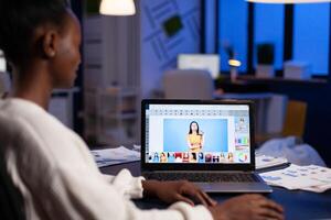 Creative african american retoucher working at design production retouching photography using editing software technology. Photographer on laptop. Woman overworking in creativity office at night photo