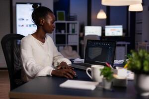 Technician engineer analyzing cad software 3D concept of container working in start-up company late at night. African american woman developing industrial prototype using construction technology photo