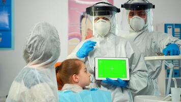 Stomatologist with coverall pointing at mockup greenscreen display during coronavirus epidemic. Explaining using monitor with green screen monitor chroma key izolated chroma pc key mock-up touchscreen photo