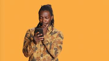 Modern guy navigating online websites on smartphone, checking his chats for texts and posing on camera. African american person using mobile apps to stay connected with friends. Handheld shot. photo