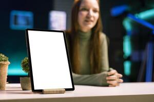 Focus on mockup tablet with gen Z teenager in blurry background doing review, comparing features. Close up shot of isolated screen portable device analyzed by influencer, filming online photo