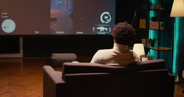 Man playing shooter videogame on TV with gun shooting laser bullets at flying robots in dark atmospheric industrial setting. Gamer enjoying competitive PvP fps internet multiplayer tournament game photo