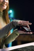 Joyous gen Z entertainer presenting wired gaming mouse from brand sponsoring , urging viewers to buy it. Upbeat tech guru excited to promote computer peripherals to audience, close up photo