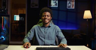 BIPOC man using gaming keyboard to play videogames at home, focused on winning. Gamer using neon lit PC and computer peripherals to compete in internet multiplayer game competition photo