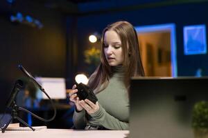 Gen Z content creator reviews large capacity V mount battery used to power high end devices on niche online channel. Girl showcasing rechargeable portable lithium power source photo