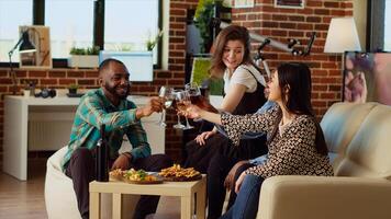 diverso grupo de personas celebrando su amistad juntos, tintinamente vino lentes a Departamento fiesta. contento amigos teniendo reunión reunión, tostado alcohólico bebidas foto