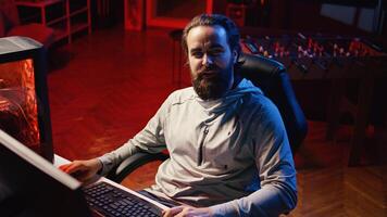 Content creator looking at webcam, chatting with audience while playing online multiplayer videogame on PC, contending against other live esports pro players, broadcasting game on internet for fans photo
