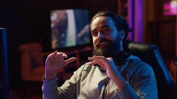Content creator playing videogames live while chatting with online audience from RGB lit studio. Professional gamer streaming multiplayer game while discussing his strategies with fans photo