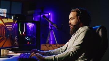 Man playing science fiction FPS videogame with friends, having fun in dark apartment room. Gamer competing in PvP online multiplayer game, talking with internet players through headphones mic photo