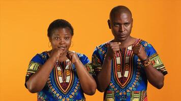 Aggressive strong people clenching fists on camera and preparing for boxing fight. Furious violent ethnic couple acting dangerous and being ready to beat someone, battle conflict. photo