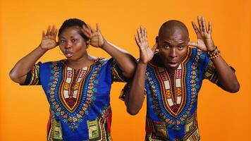 African american silly couple fooling around on camera, sticking tongue out and having fun with jokes in studio. Ethnic man and woman laughing together and acting playful. photo