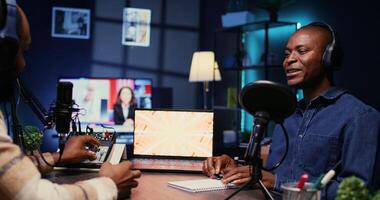 African american influencer recording podcast with man, talking in studio. Zoom in shot of cheerful man listening to guest live during broadcasting session for internet show photo