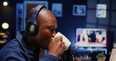 African american show host recording podcast with guest, using analog mixer and professional mic in studio. Close up shot of man setting up audio devices for live broadcast for flawless sound quality photo
