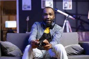 Player showing confused face after seeing game over screen, losing singleplayer videogame on console system at home. Portrait of african american man puzzled after being unexpectedly being defeated photo