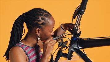 BIPOC technician uses screwdriver to unmount bicycle handlebars, testing components quality in studio background atelier shop. Specialist mechanic unscrewing bike parts in order to mend them, camera A photo